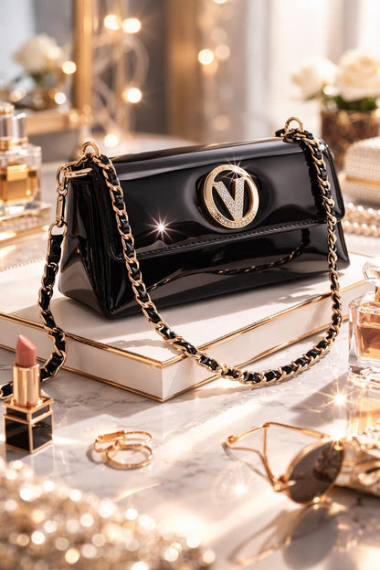 Black patent leather evening clutch with crystal V clasp and gold chain crossbody strap by Lace & Luxe.
