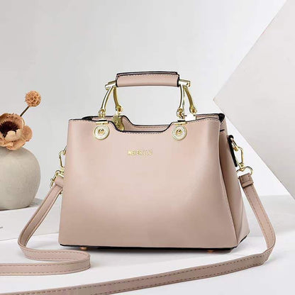 Blush pink structured satchel handbag with gold hardware, top handle, and crossbody strap made of vegan leather for women.