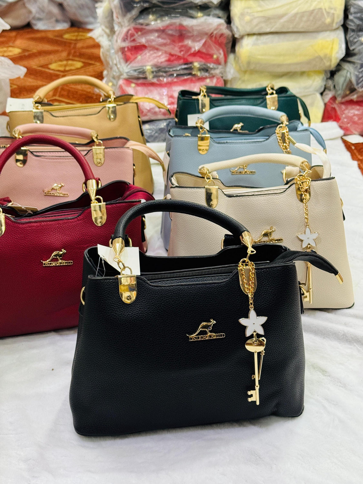 Leather top handle handbag by Lace & Luxe with gold key charm, structured shoulder bag design, featuring sleek leather and elegant details.
