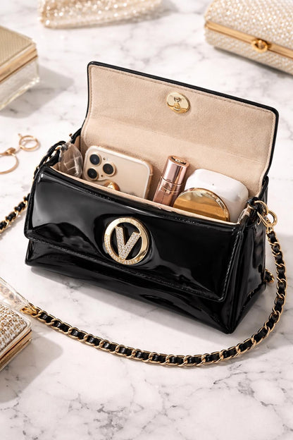 Black patent leather evening clutch with gold chain crossbody strap and crystal V clasp, by Lace & Luxe.